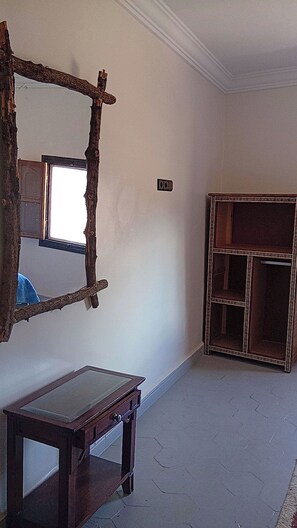 A room with a rustic mirror, a small wooden table, and a cabinet with a decorative frame. - Tagtout (Tafraout)