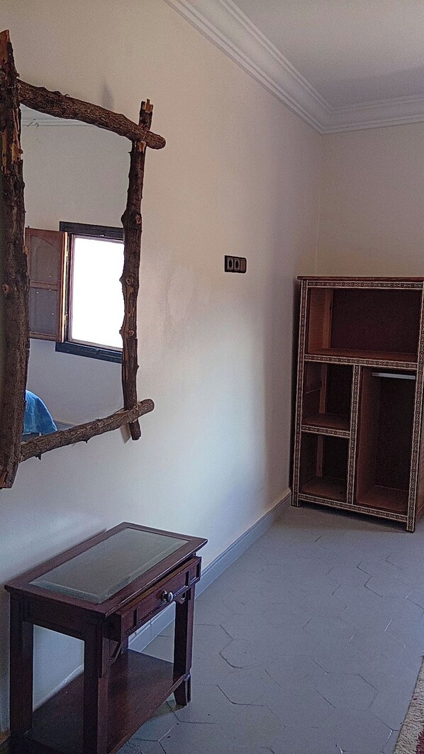 A room with a rustic mirror, a small wooden table, and a cabinet with a decorative frame.