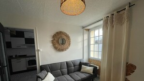 A modern living room with a dark grey sofa, a woven light fixture, and a decorative wall piece.