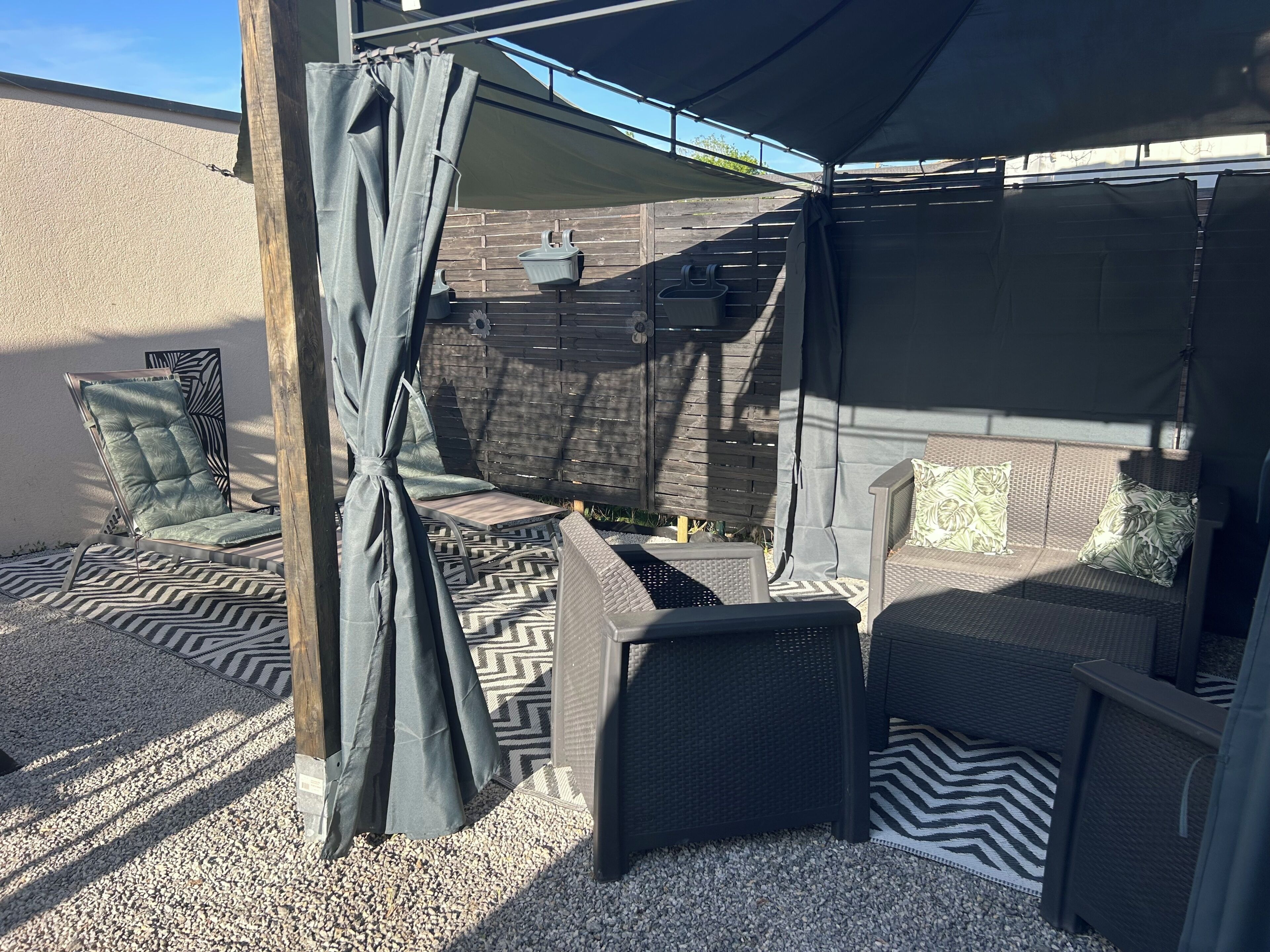 A patio with outdoor furniture, a pergola, and a wall-mounted planter.