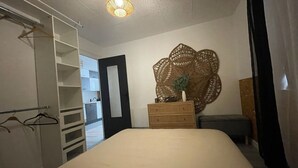 A bedroom with a bed, a dresser, a mirror, and a wardrobe.