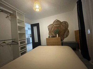 A bedroom with a bed, a dresser, a mirror, and a wardrobe.