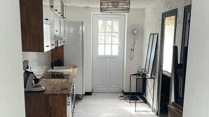 A hallway with a kitchen on the left, a dining area with a table and chairs, and a large window at the end.