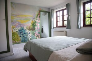 Un dormitorio con cama, radiador, ventana con cortinas y una puerta que da a otra habitación.