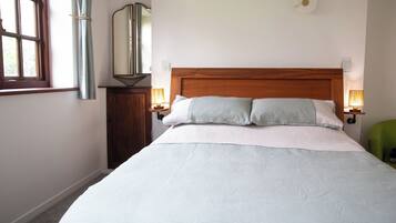 A neatly made bed with a wooden headboard, two bedside lamps, and a mirror on the wall.