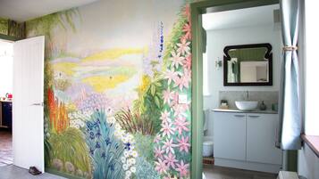 A room with a mural of flowers and a bathroom with a sink and mirror.