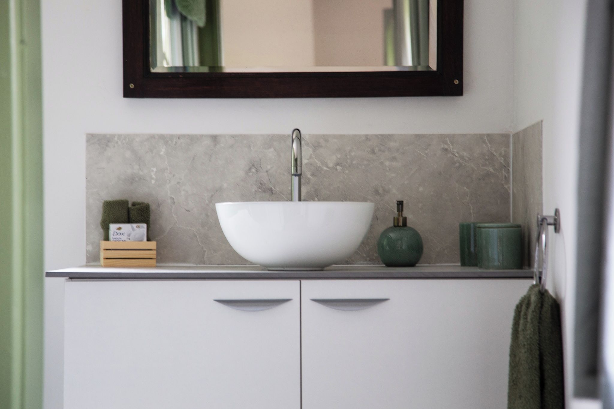 A bathroom with a white sink, a green soap dispenser, and a mirror above the sink.