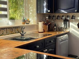 Una cocina con un lavamanos doble, encimera de madera y lavavajillas.