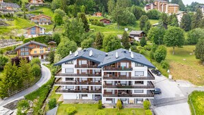 Um hotel com vários andares e varandas, rodeado por vegetação exuberante e outros edifícios.