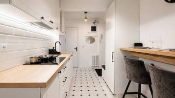 A modern kitchen with white cabinets, a wooden countertop, a black faucet, and a tiled floor.