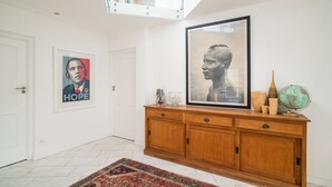 A hallway with a wooden cabinet, a framed portrait, and a rug. - Beachfront Designer Villa in Secure Estate (Cape Town)