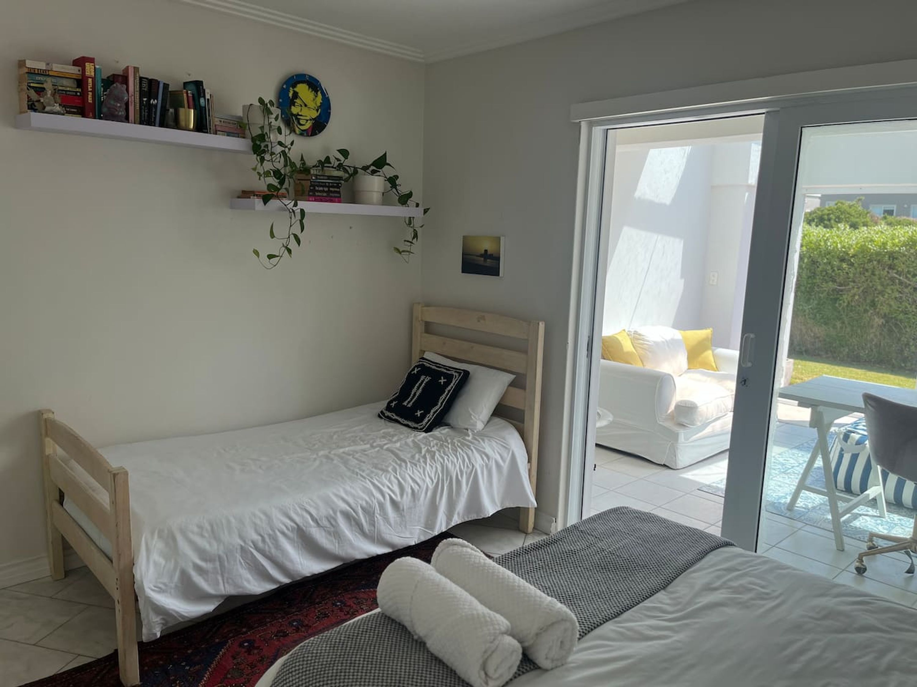 Een slaapkamer met twee bedden, een boekenkast, een plant en uitzicht op het omliggende landschap.
