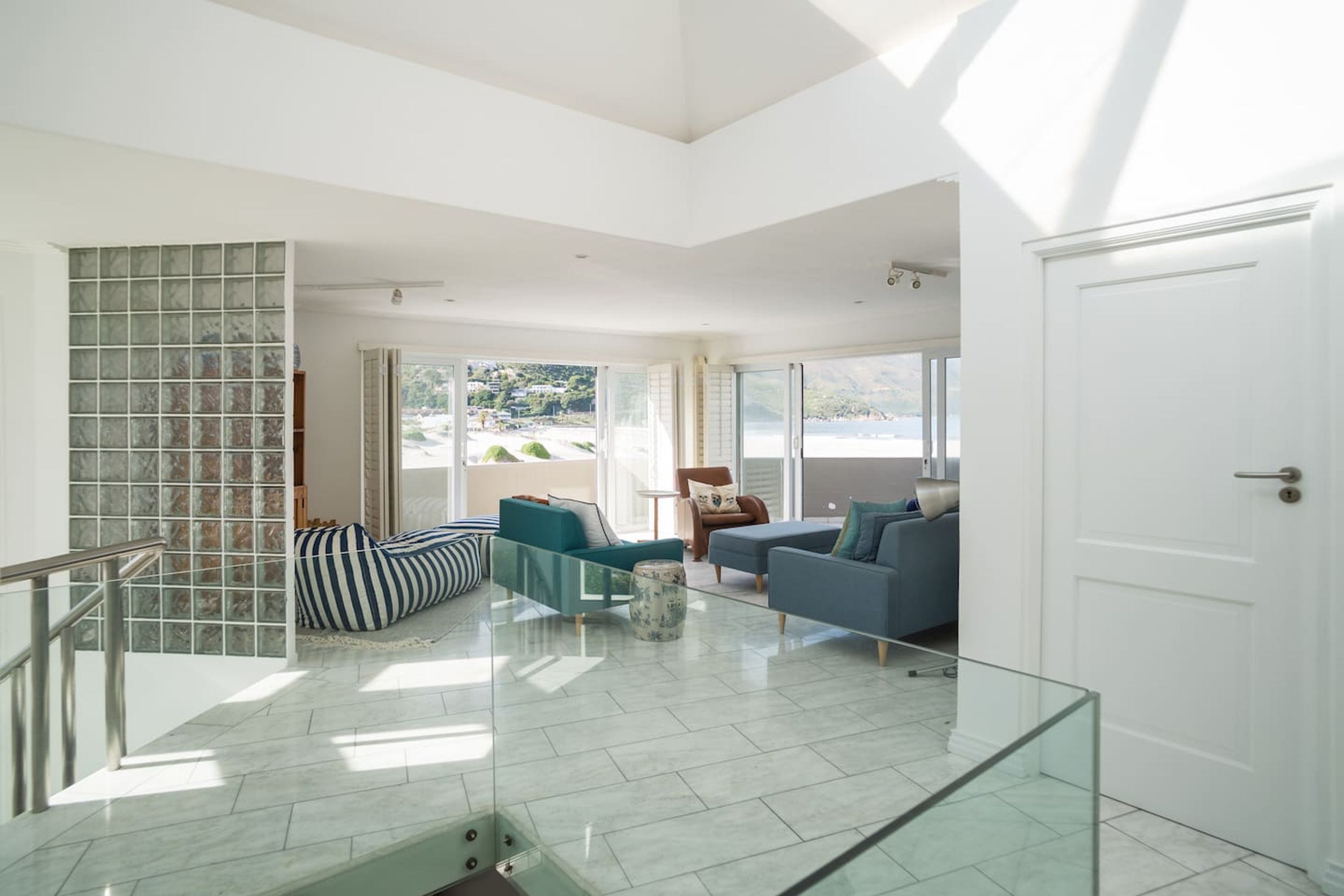 A spacious living area with a glass railing, a sofa, a chair, and a view of the outdoors.