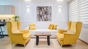 A modern living room with a sofa, two armchairs, a coffee table, and a large abstract painting on the wall. - Luxury Apt in Heart Gueliz  Panoramic City Views MARRAKECH (Marrakech)