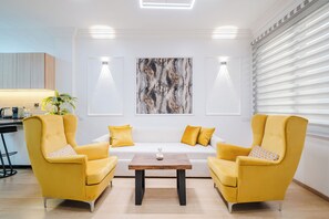 A modern living room with a sofa, two armchairs, a coffee table, and a large abstract painting on the wall. - Luxury Apt in Heart Gueliz  Panoramic City Views MARRAKECH (Marrakech)