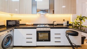 A modern kitchen with a built-in washing machine, a microwave, a stove, and a sink. - Luxury Apt in Heart Gueliz  Panoramic City Views MARRAKECH (Marrakech)