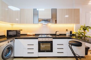 A modern kitchen with a built-in washing machine, a microwave, a stove, and a sink. - Luxury Apt in Heart Gueliz  Panoramic City Views MARRAKECH (Marrakech)