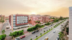 A modern building with a unique facade, surrounded by a well-maintained street with cars and greenery. - Luxury Apt in Heart Gueliz  Panoramic City Views MARRAKECH (Marrakech)