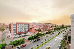 A modern building with a unique facade, surrounded by a well-maintained street with cars and greenery. - Luxury Apt in Heart Gueliz  Panoramic City Views MARRAKECH (Marrakech)