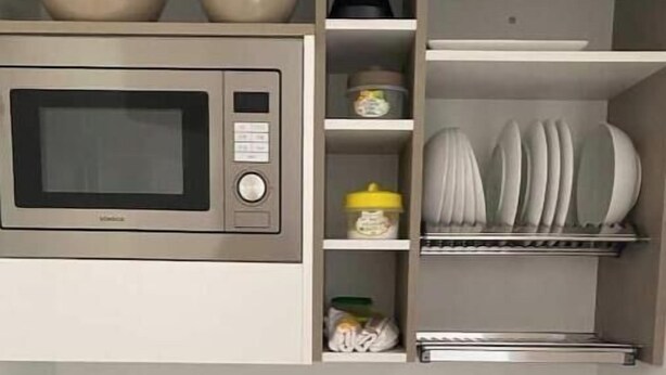 Une cuisine équipée d’un four à micro-ondes, d’un évier et d’étagères de rangement.