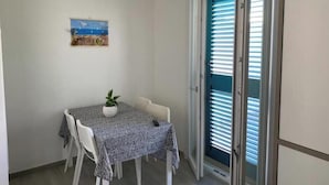Un coin repas comprenant une table, des chaises, une plante en pot et un tableau accroché au mur.