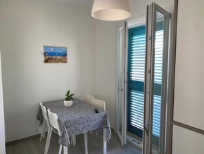 A dining area with a table, chairs, a potted plant, and a painting on the wall. - Amida App.to, Cielo, 1st Floor (Campomarino di Maruggio (TA))