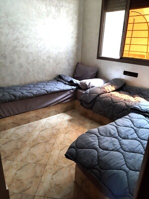 Ein Schlafzimmer im Eck mit Bett, kleinem Tisch und Fenster.