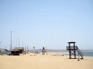 Ein Strand mit Rettungstürmen, einem kleinen Gebäude und einem Zaun.