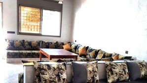 A living room with a sectional sofa, a wooden coffee table, and a chandelier.