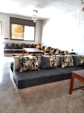 Ein Wohnzimmer mit einem Ecksofa, einem Couchtisch aus Holz und einer Pendelleuchte.