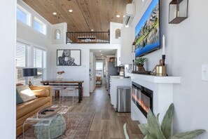 Ein großzügiger Wohnbereich mit Kamin, einem Esstisch und einer Küche im Hintergrund.