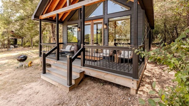 Eine Holzhütte mit Veranda, Sitzgelegenheit im Freien und Grill.