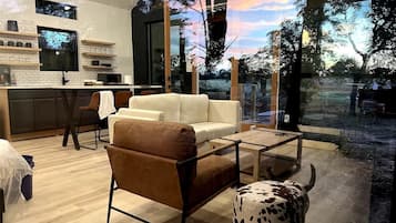 A modern living room with a sofa, armchair, coffee table, and a decorative cow sculpture.