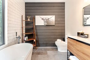 Un bagno moderno con vasca, servizi igienici e una mensola in legno.