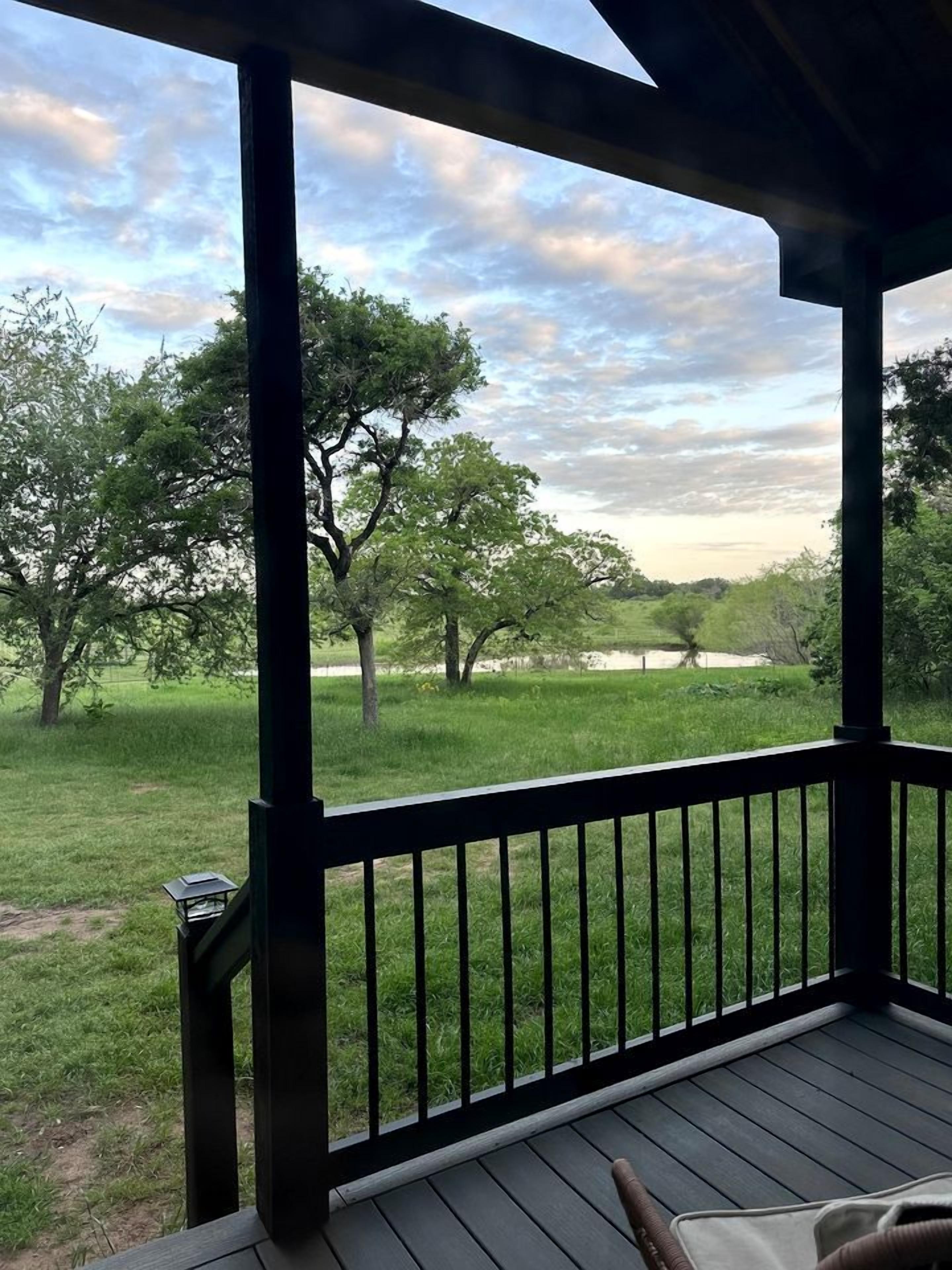 Una terraza de madera con vista a un campo cubierto de césped y árboles.