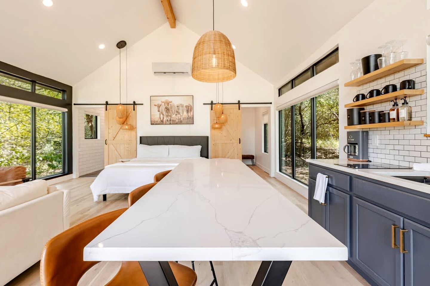 A modern kitchen with a large island, wooden cabinets, and a view of the outdoors.