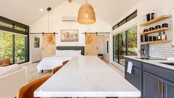A modern kitchen with a large island, wooden cabinets, and a view of the outdoors.