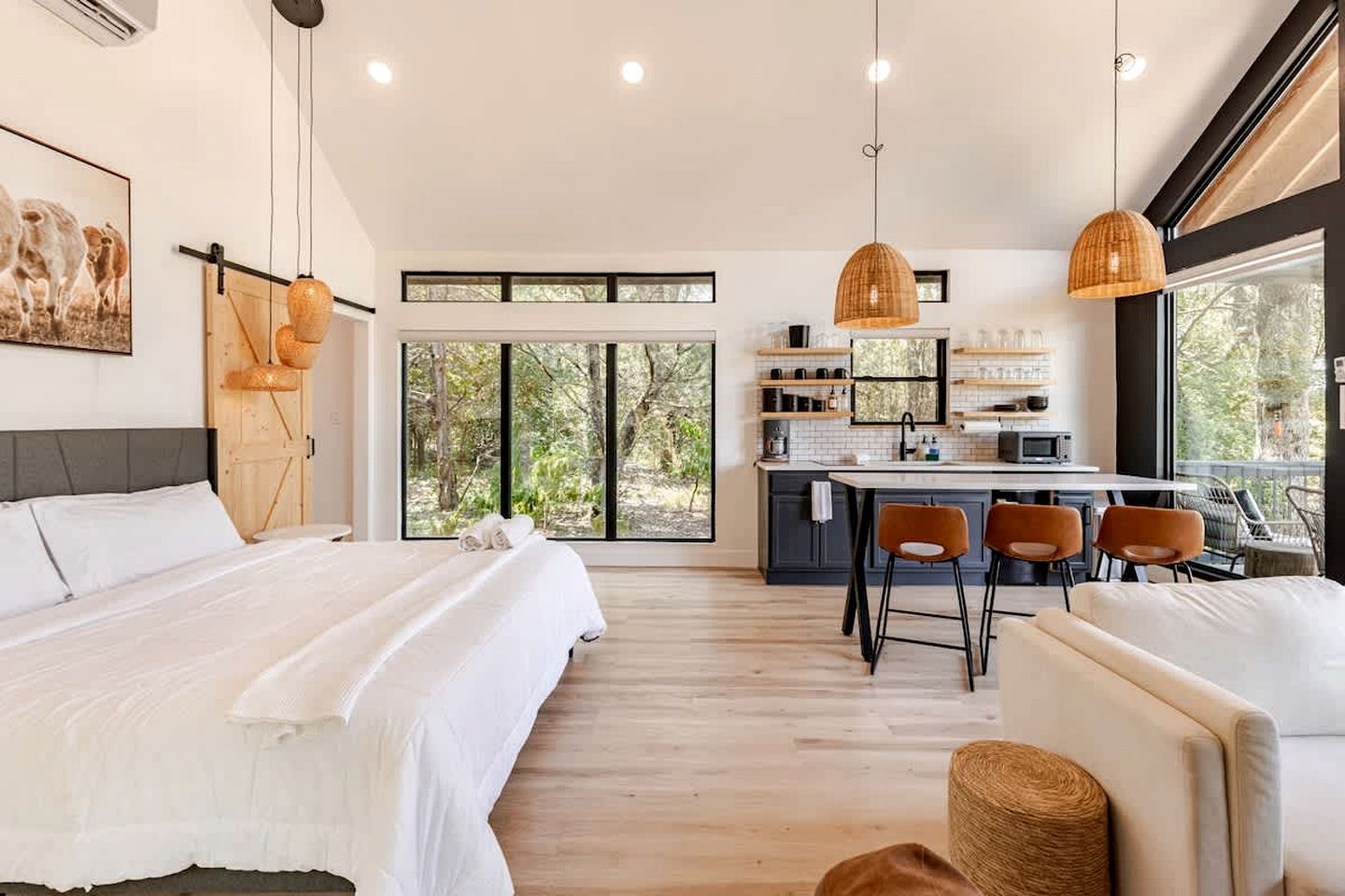 Une chambre moderne avec un grand lit, un coin repas avec des chaises et une cuisine avec un bar.