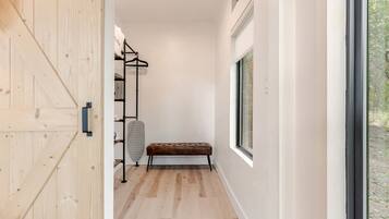 A hallway with a wooden door, a bench, a radiator, and a window with a view of trees.