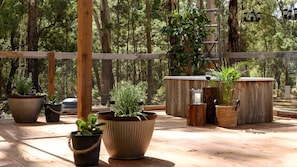 A wooden deck with potted plants, a metal coffee pot, and a wooden barrel. - Secluded Wooden Cabin with Barbecue in Daylesford, Victoria (Wheatsheaf)