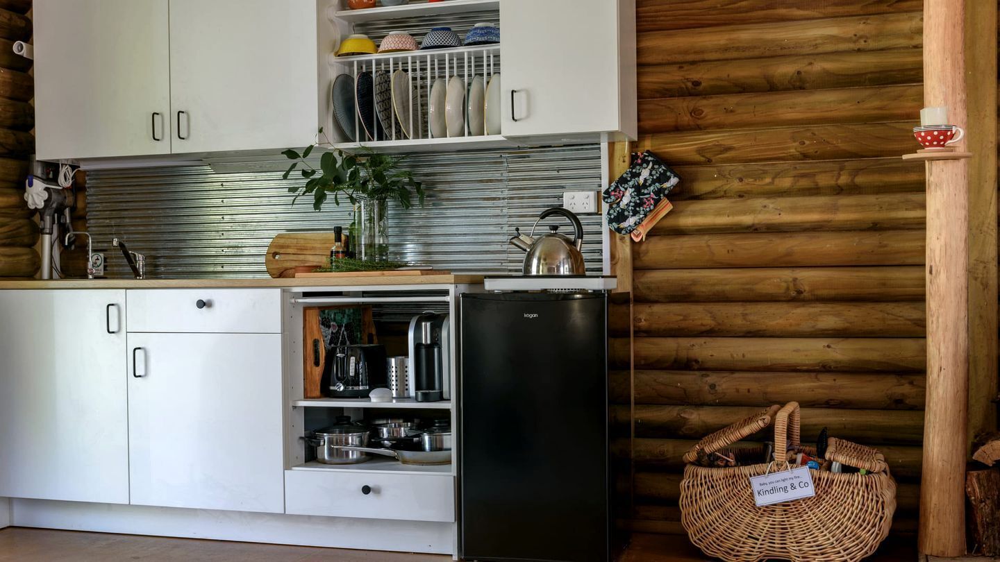 A kitchen with white cabinets, a black refrigerator, and a woven basket on the counter.