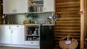 A kitchen with white cabinets, a black refrigerator, and a woven basket on the counter.
