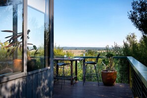 Ein Balkon mit Tisch und Stühlen, einem Blumentopf und Blick auf die Landschaft.