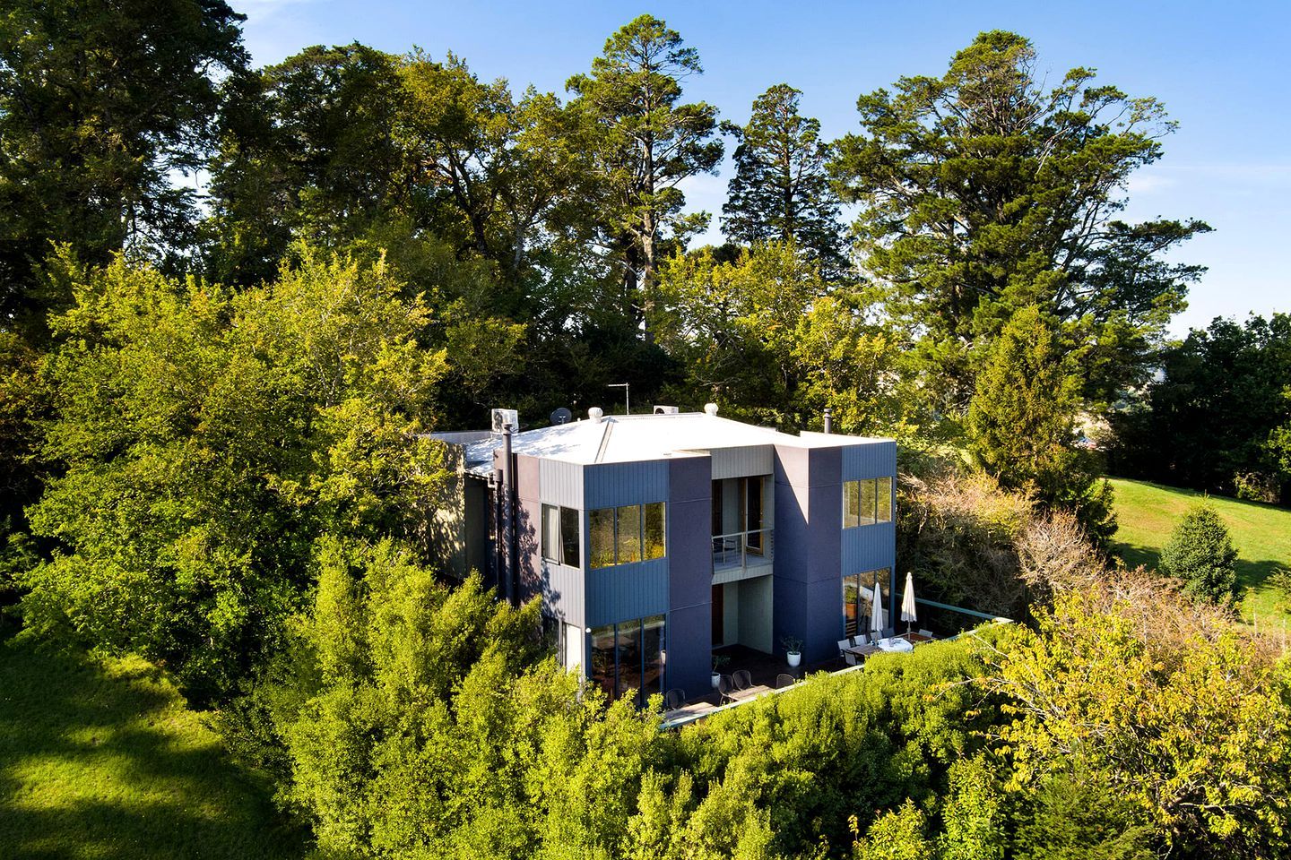 A modern two-story building surrounded by dense greenery.