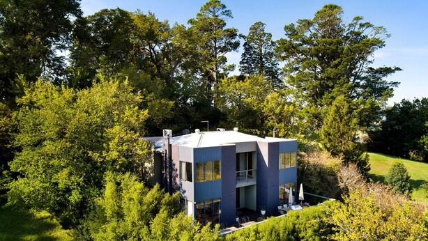 Un bâtiment moderne à deux étages, entouré d’une végétation luxuriante.