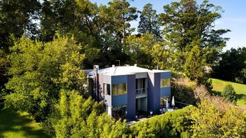 A modern two-story building surrounded by dense greenery.