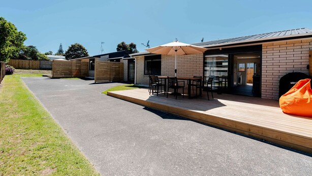 Un espace extérieur moderne, aménagé en patio, avec une table et des chaises, une terrasse en bois et un coin salon abrité.