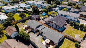 Vue aérienne d’un quartier résidentiel avec plusieurs maisons, une maison principale dotée d’un patio et une cour clôturée.