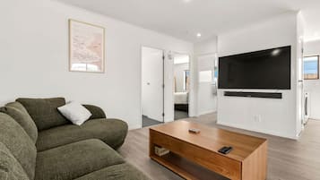 A modern living room with a sofa, a coffee table, and a flat-screen TV mounted on the wall.