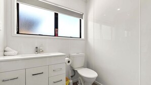 Une salle de bain moderne équipée de toilettes, d’un lavabo et de meubles de rangement.